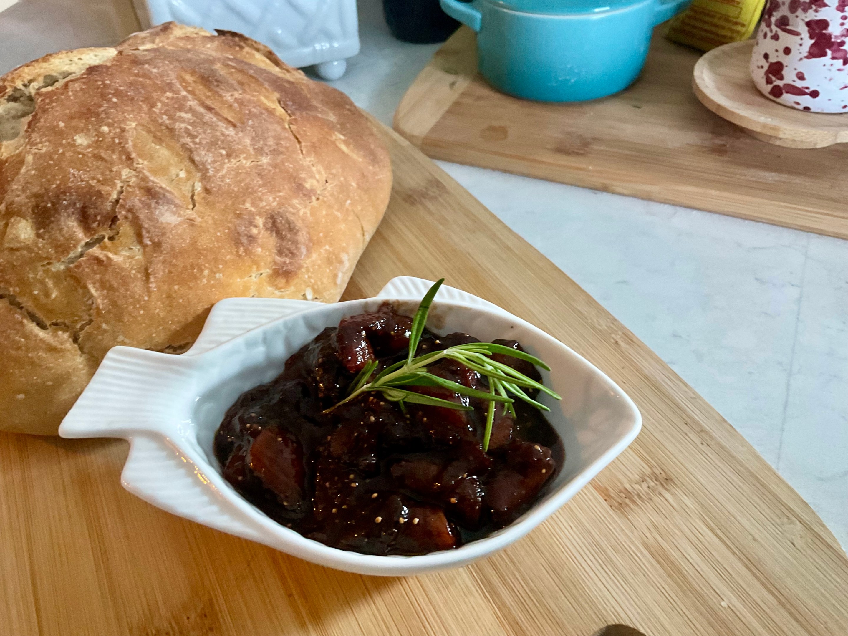 Bowl of homemade fig preserve with a loaf of rustic bread.