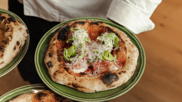 Wood-fired pizzetta topped with prosciutto, cheese, and fresh greens at Massara.