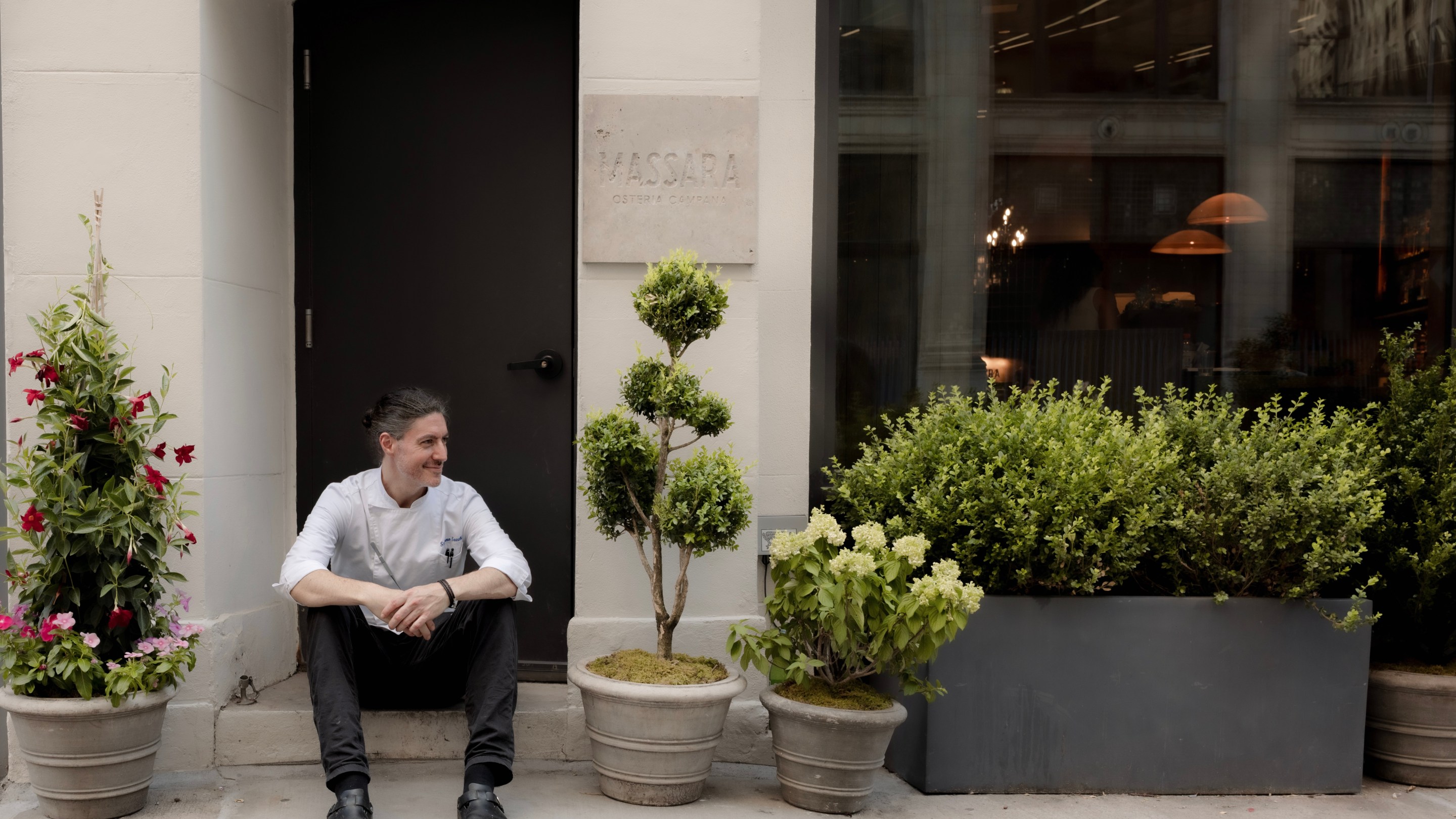 Chef Stefano Secchi sitting outside the entrance to Massara restaurant in New York City.