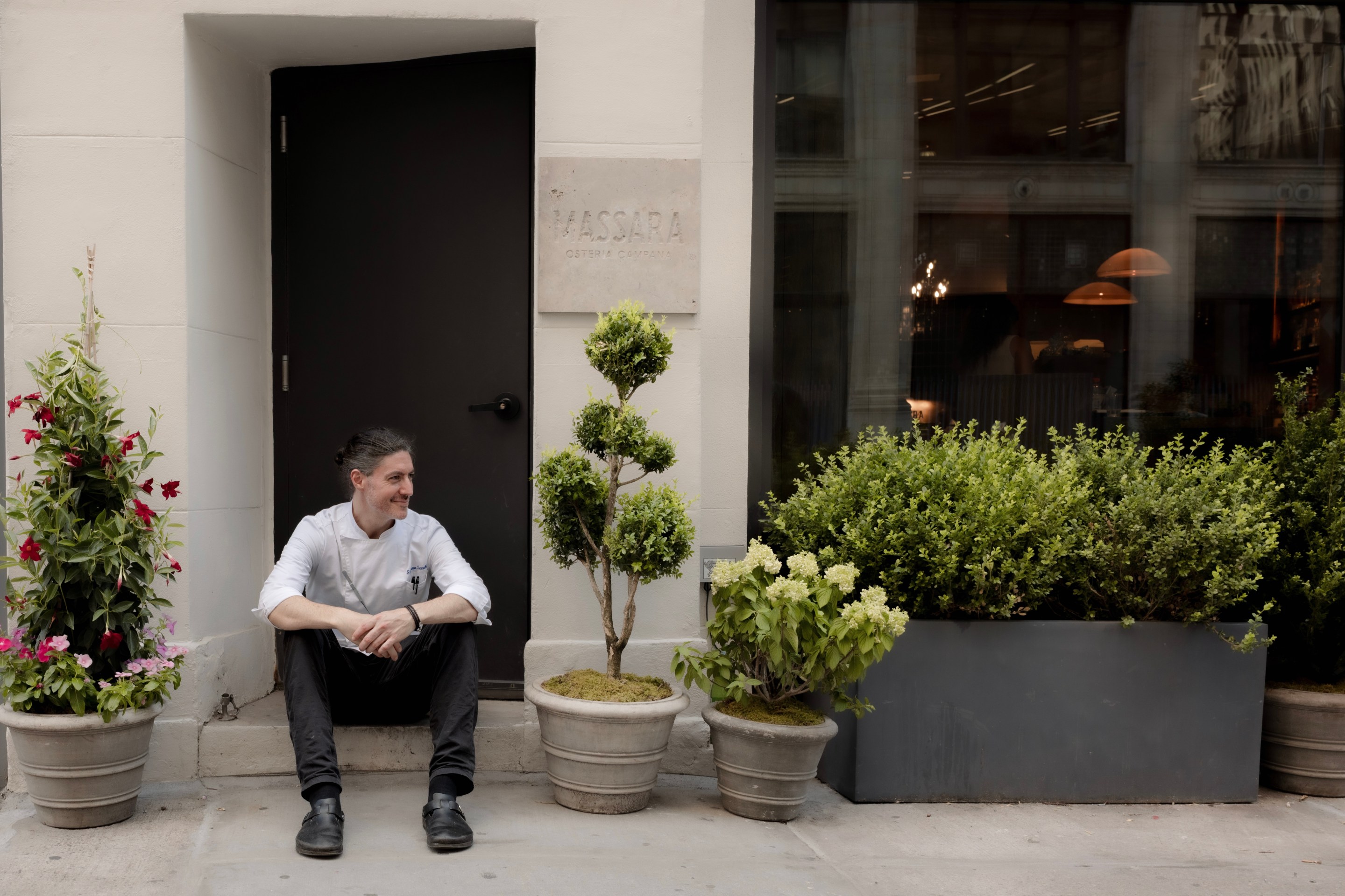 Chef Stefano Secchi sitting outside the entrance to Massara restaurant in New York City.