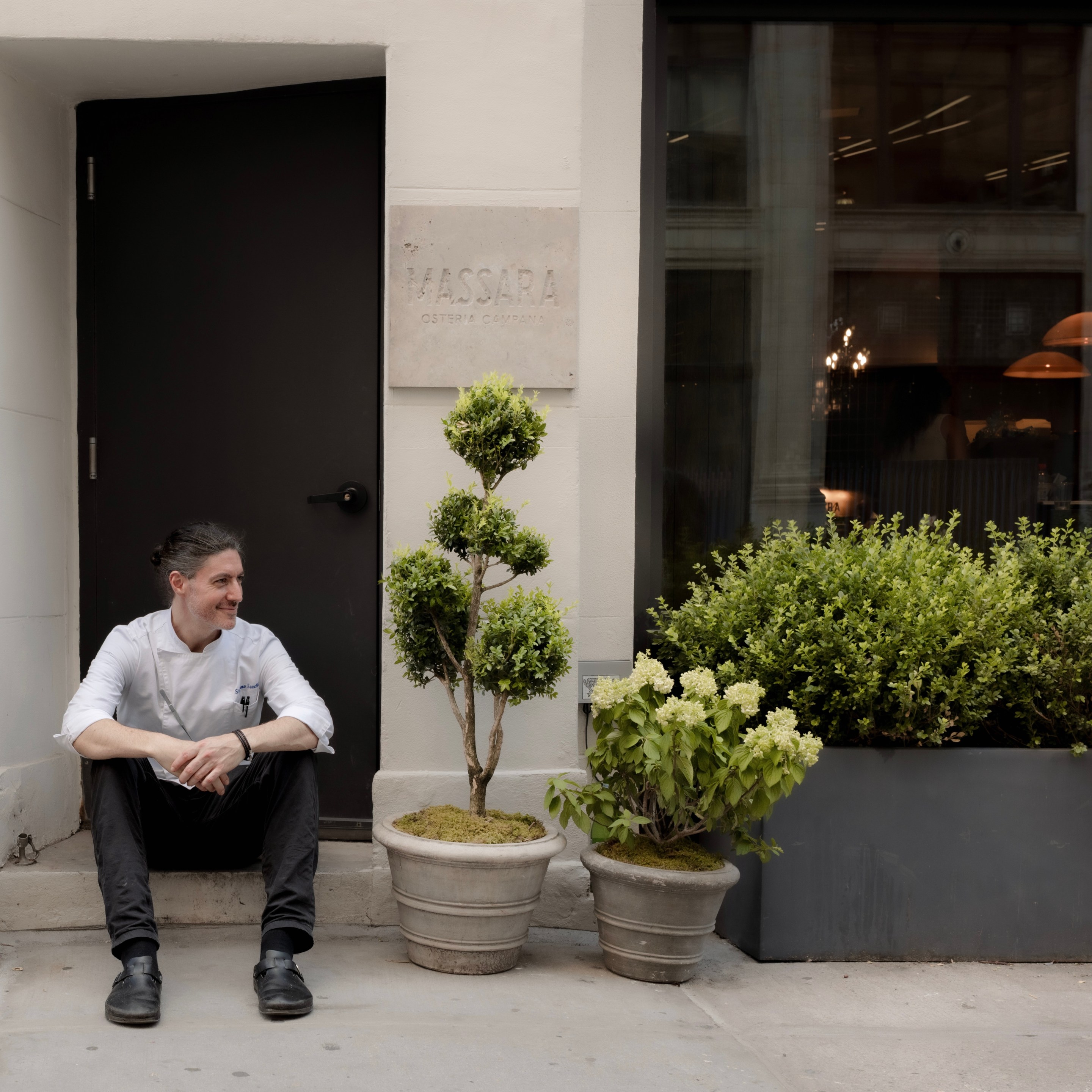 Chef Stefano Secchi sitting outside the entrance to Massara restaurant in New York City.