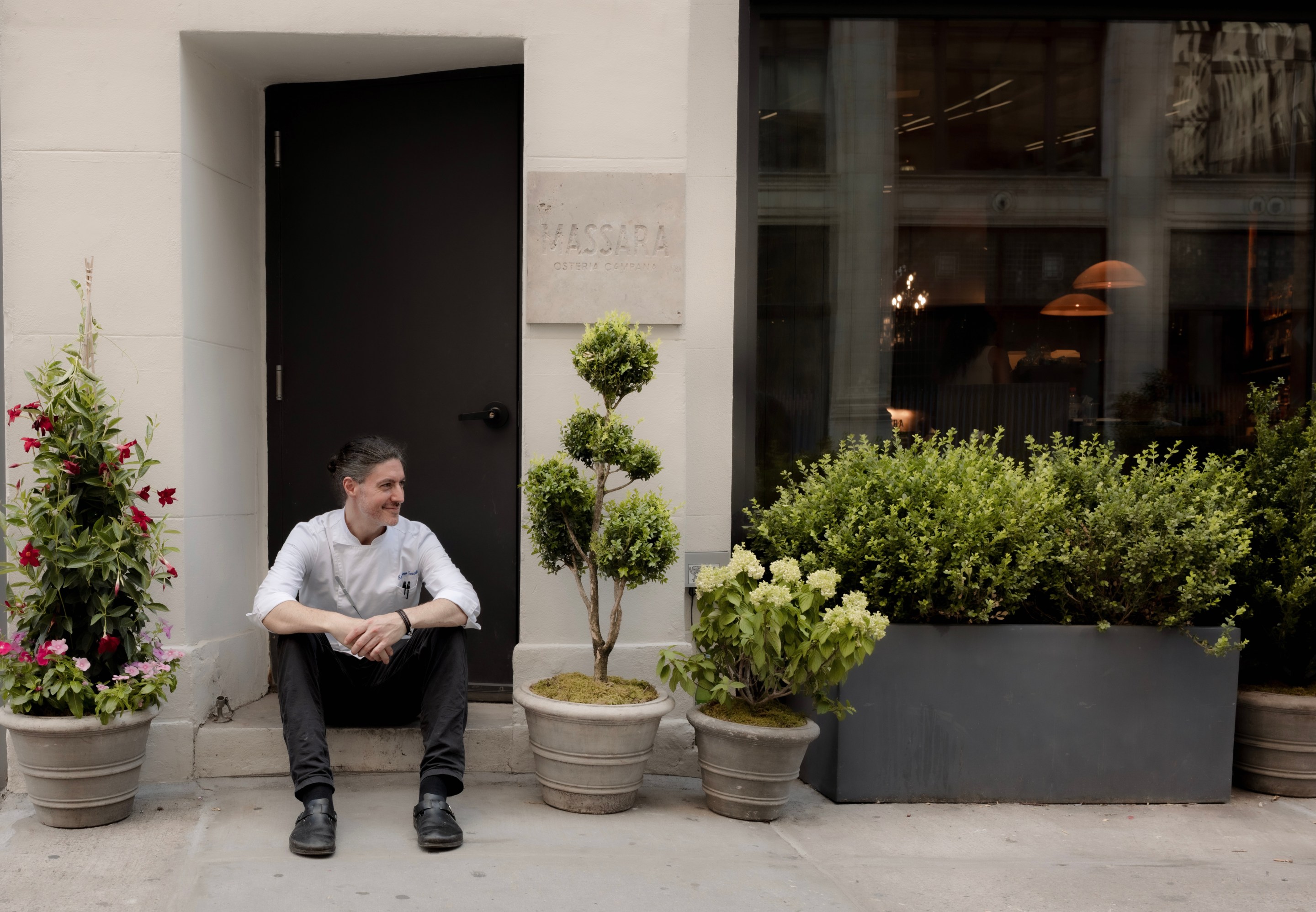 Chef Stefano Secchi sitting outside the entrance to Massara restaurant in New York City.