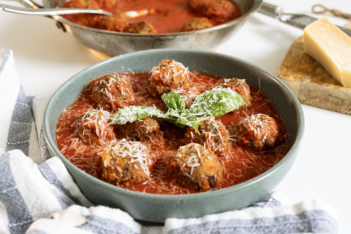 Golden fried eggplant meatballs simmer in homemade marinara before serving.