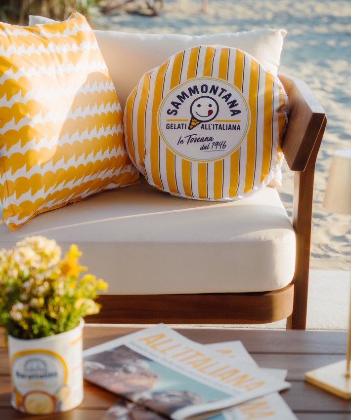 Sammontana branded decorative pillow on outdoor lounge seating overlooking the beach.