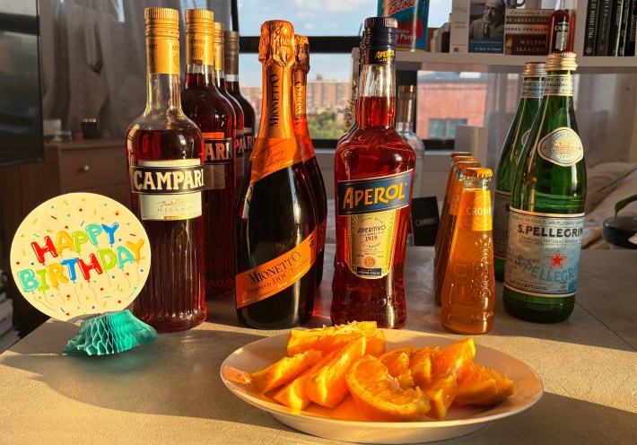 Campari, Aperol, prosecco, sparkling water, oranges and Crodino arranged for a make-your-own spritz station.