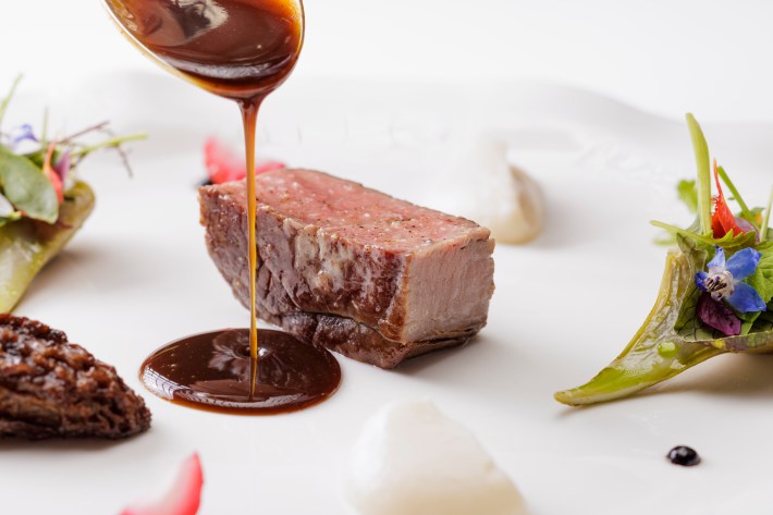 Sauce being poured over veal at Luca's Michelin-starred restaurant in Florence.