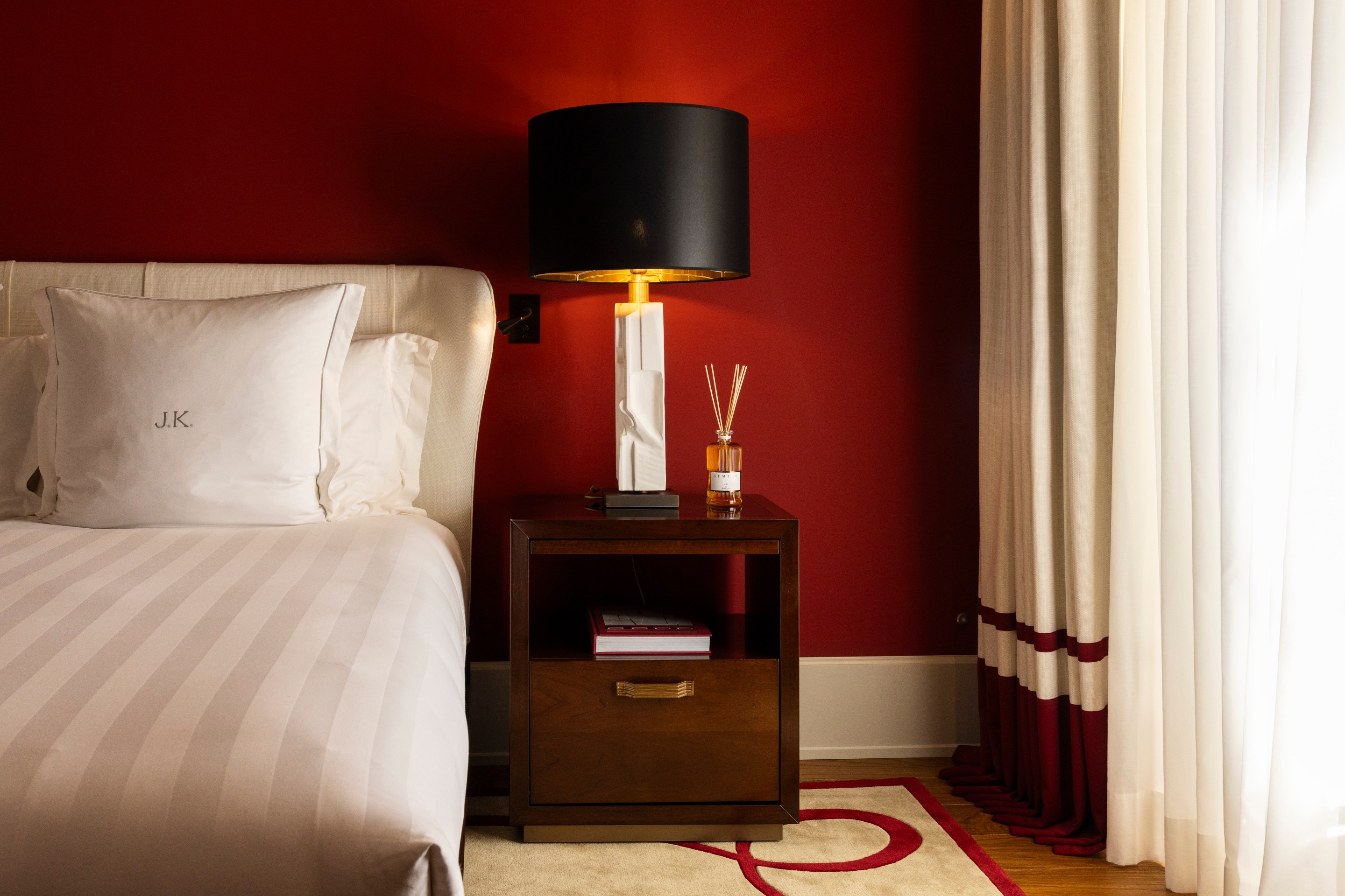 Bedroom at Casa J.K. Place Roma with red accent wall and custom furnishings.