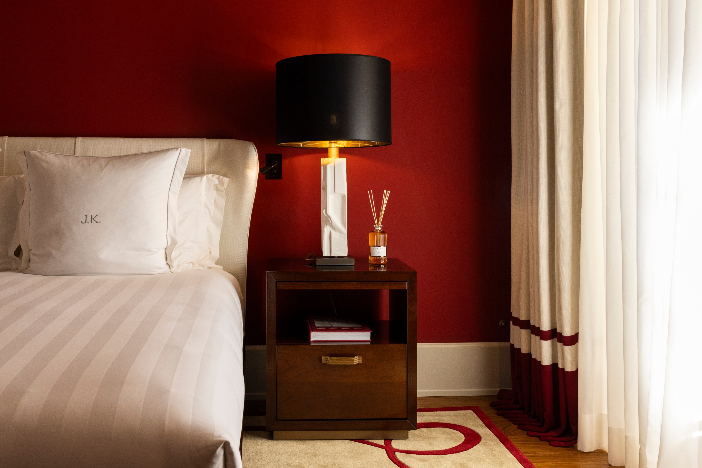 Bedroom at Casa J.K. Place Roma with red accent wall and custom furnishings.