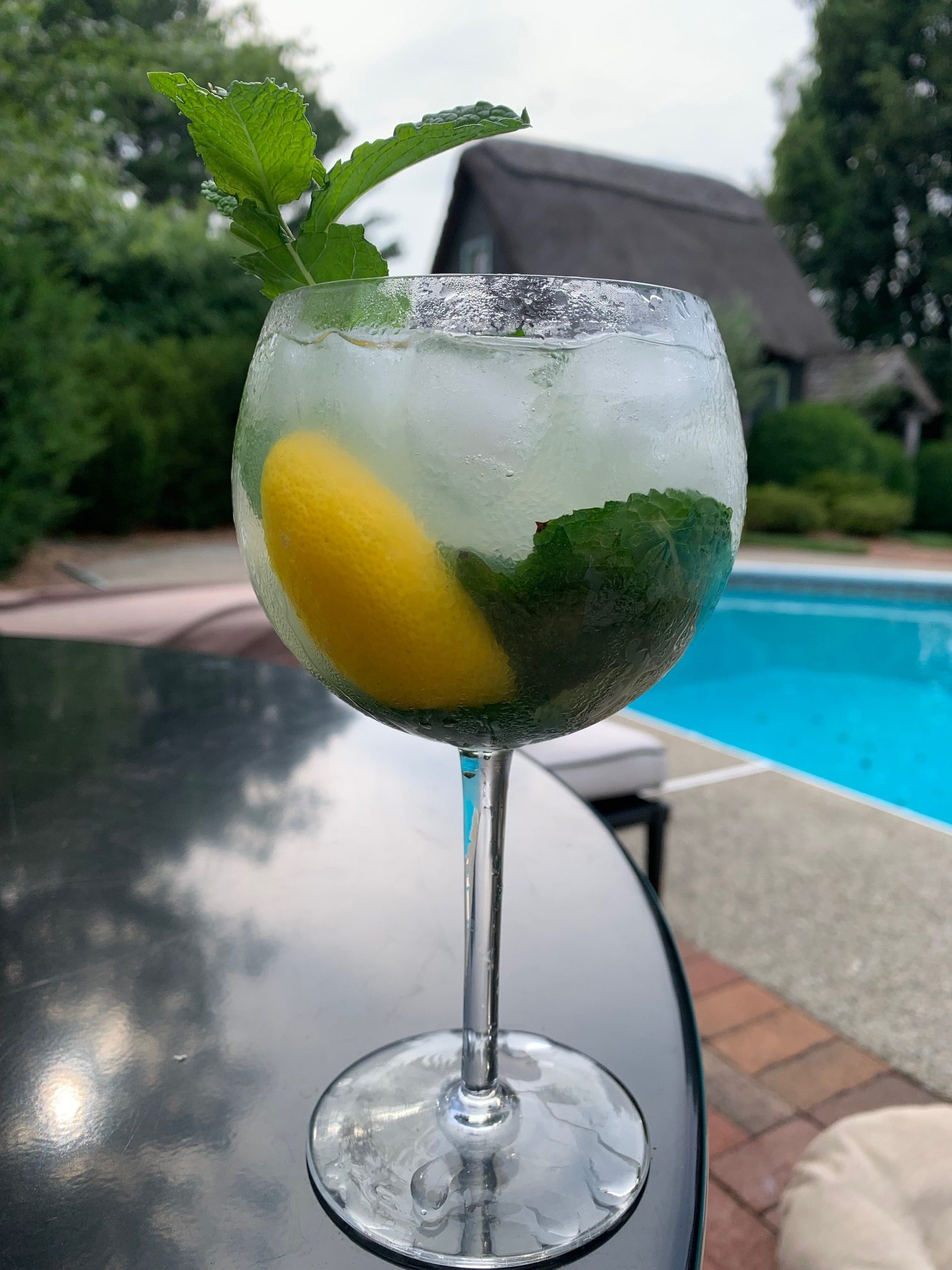 The Mancini Spritz with a twist of lemon on a table near a swimming pool