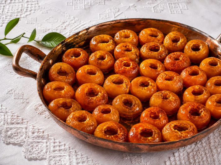 Sa pompìa intrea, the traditional honey-cooked Sardinian sweet, presented on white knotted embroidery inspired by the historic needlework of Teulada.