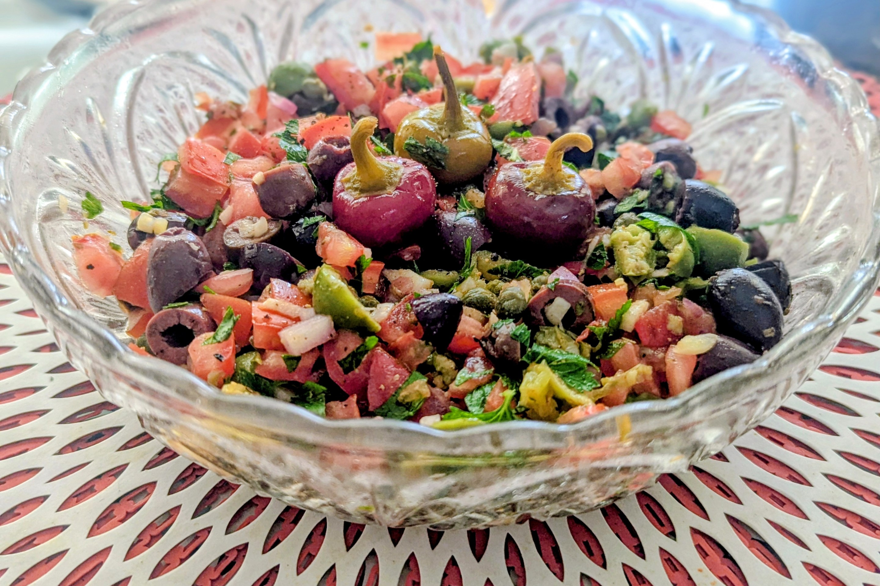 Close-up of Sicilian salsa featuring tomatoes, olives, capers, herbs, and pickled cherry peppers.