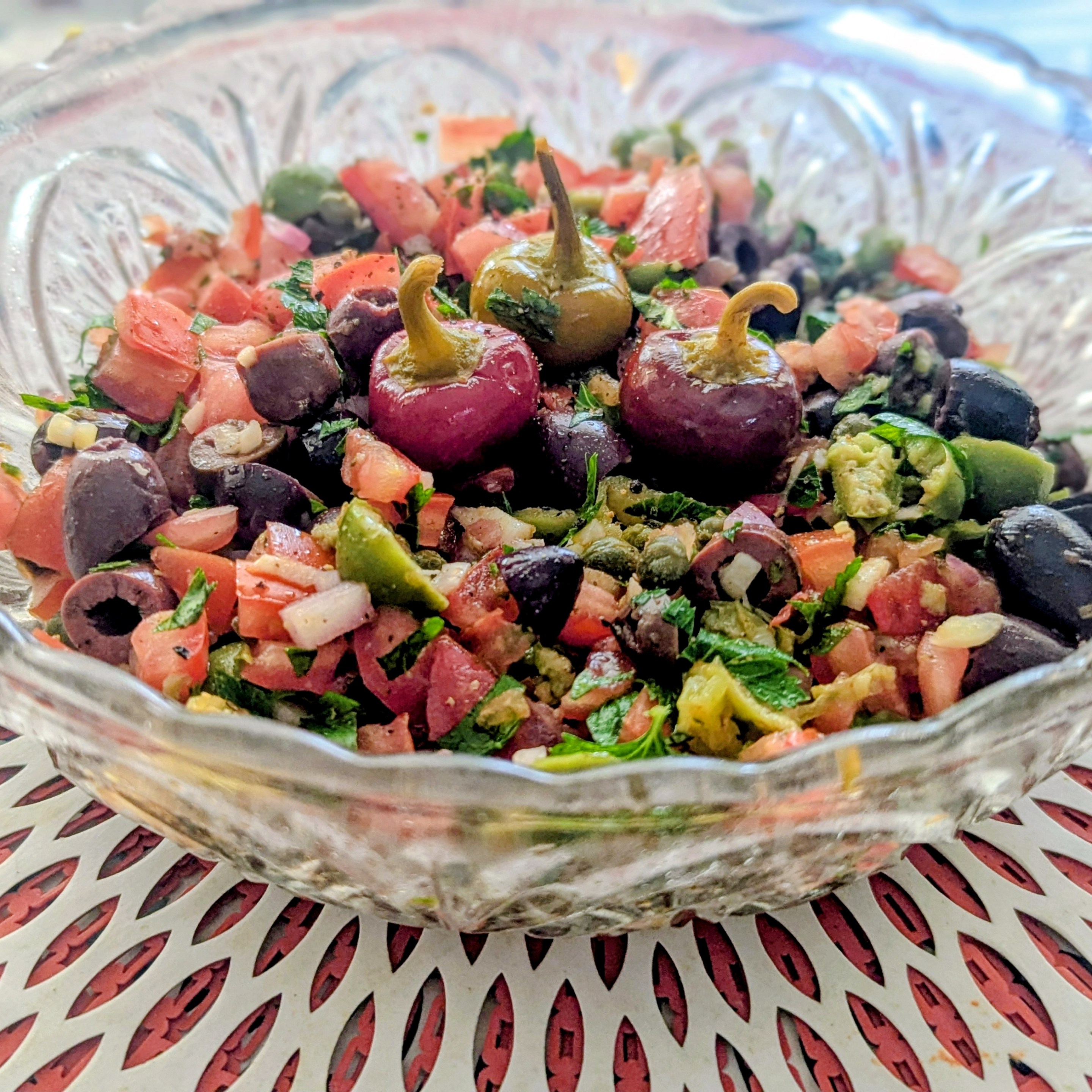 Close-up of Sicilian salsa featuring tomatoes, olives, capers, herbs, and pickled cherry peppers.