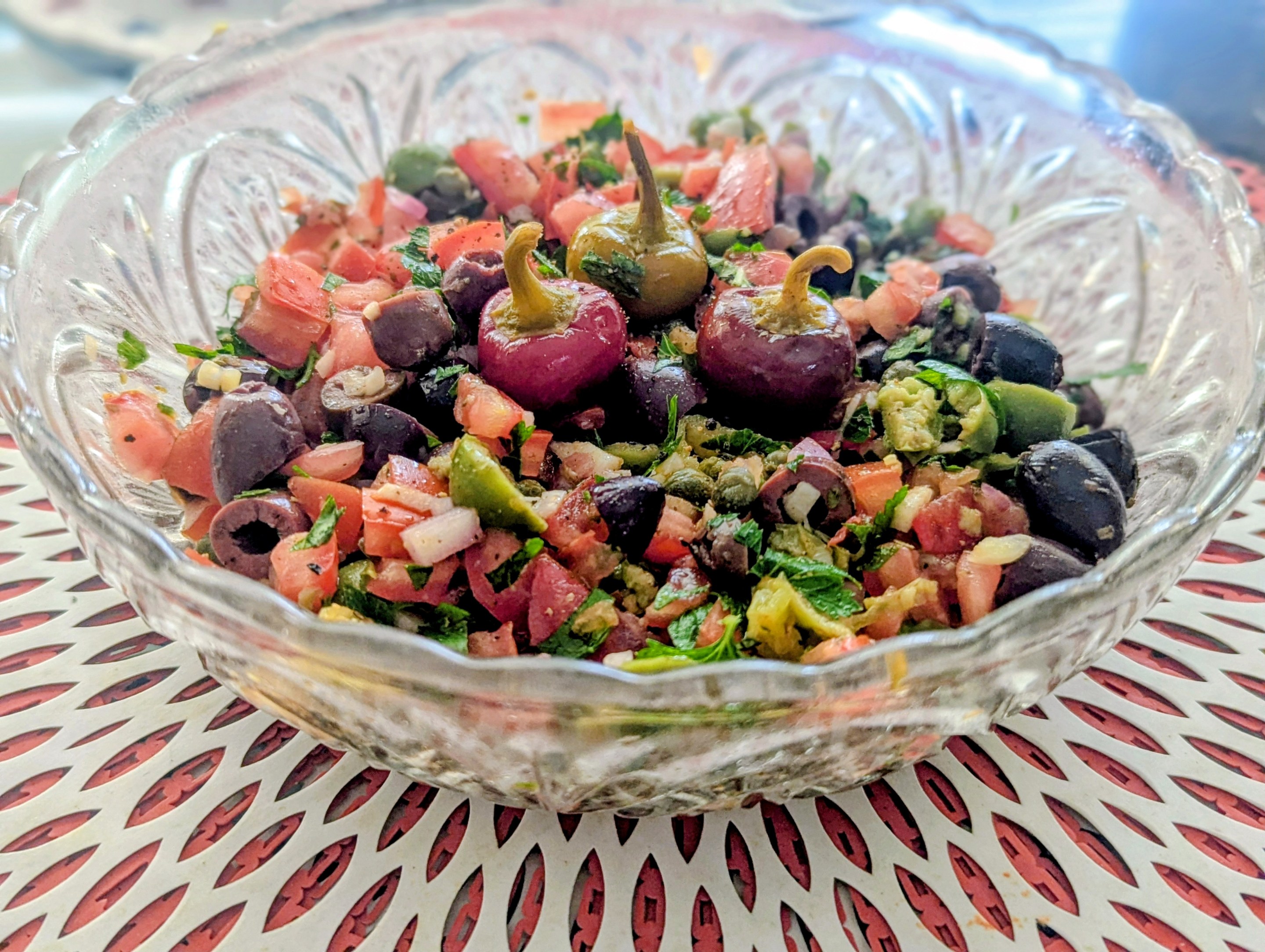 Close-up of Sicilian salsa featuring tomatoes, olives, capers, herbs, and pickled cherry peppers.