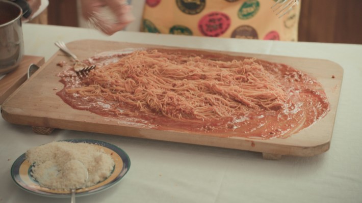 TUCCI IN ITALY - “Le Marche” - Maccheroncini di Campofilone being mixed with a red ragu on a board.