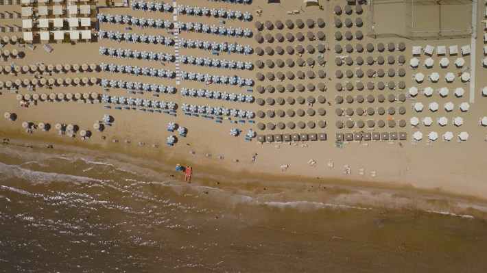 TUCCI IN ITALY - “Le Marche” - A stunning aerial view of Senigallia’s beach, with rows of colorful sun umbrellas lining the shore. (National Geographic)