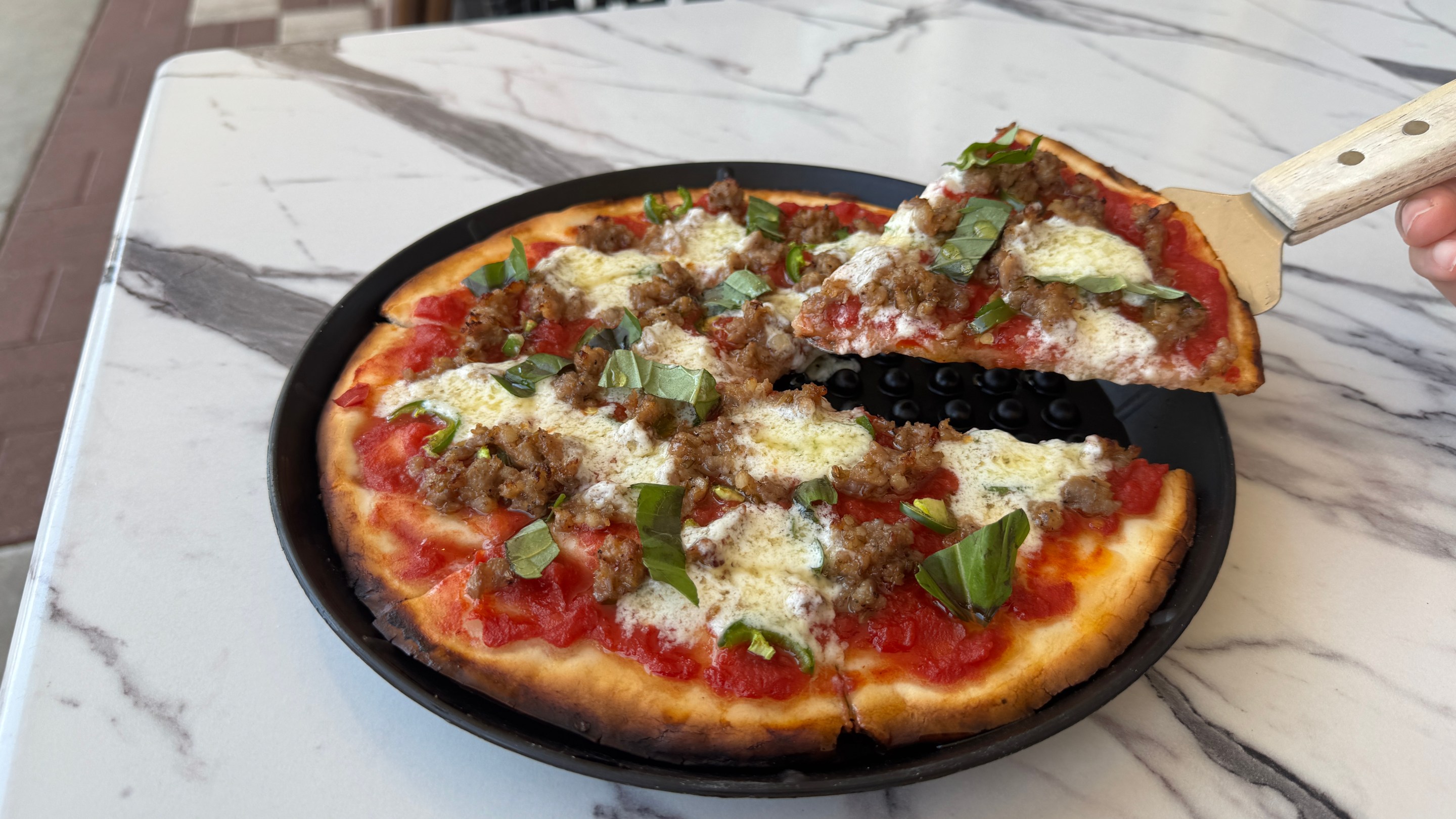 Gluten-free pizza topped with sausage, basil and cheese at Baldinucci Pizza Romana in Austin.