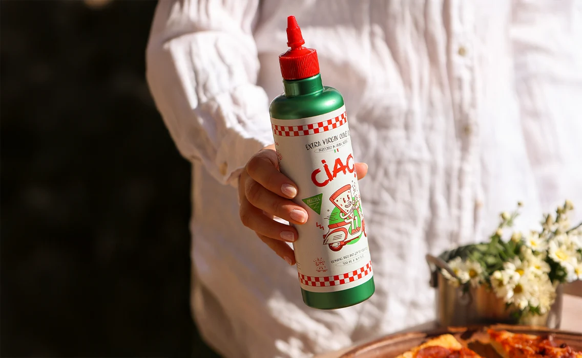 Hand holding a squeeze bottle of CIAO! Sicilian extra virgin olive oil