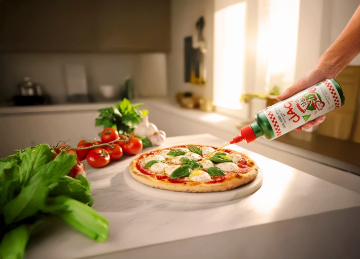 CIAO! Sicilian extra virgin olive oil being drizzled from a squeeze bottle over a Margherita pizza