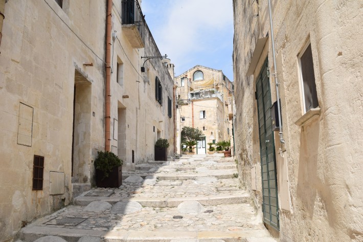 Narrow stone alleyway lined with historic buildings in Matera, Italy.