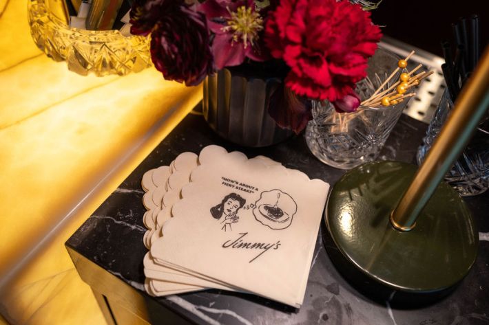 Jimmy's cocktail napkins displayed beside fresh flowers at the restaurant bar.
