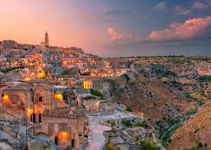 Panoramic view of Matera, Italy, illuminated at sunset above the rocky ravine.