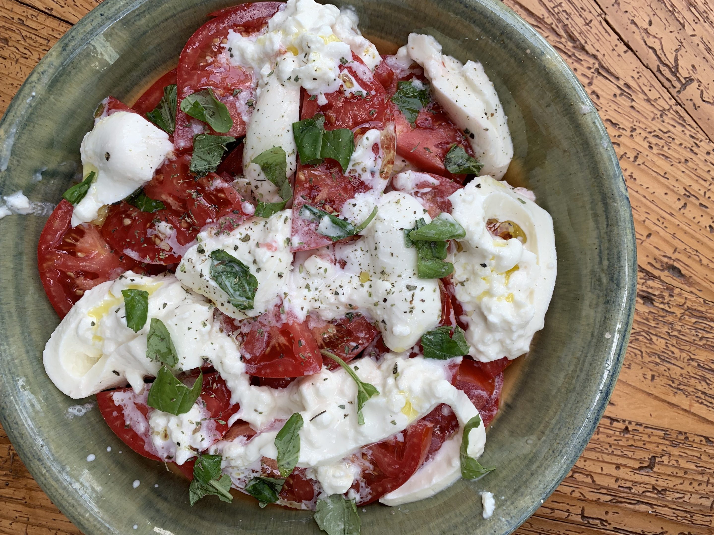 Summer tomatoes with creamy burrata, fresh basil, oregano and olive oil.