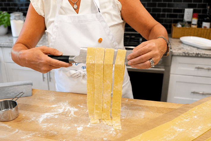 Fresh pappardelle ribbons draped over a knife.