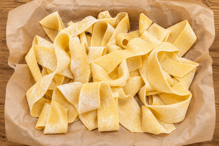 Fresh pappardelle ribbons dusted with flour.
