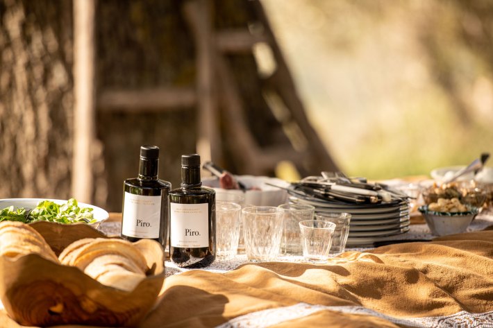 Bottles of Olio Piro extra virgin olive oil arranged on an outdoor dining table
