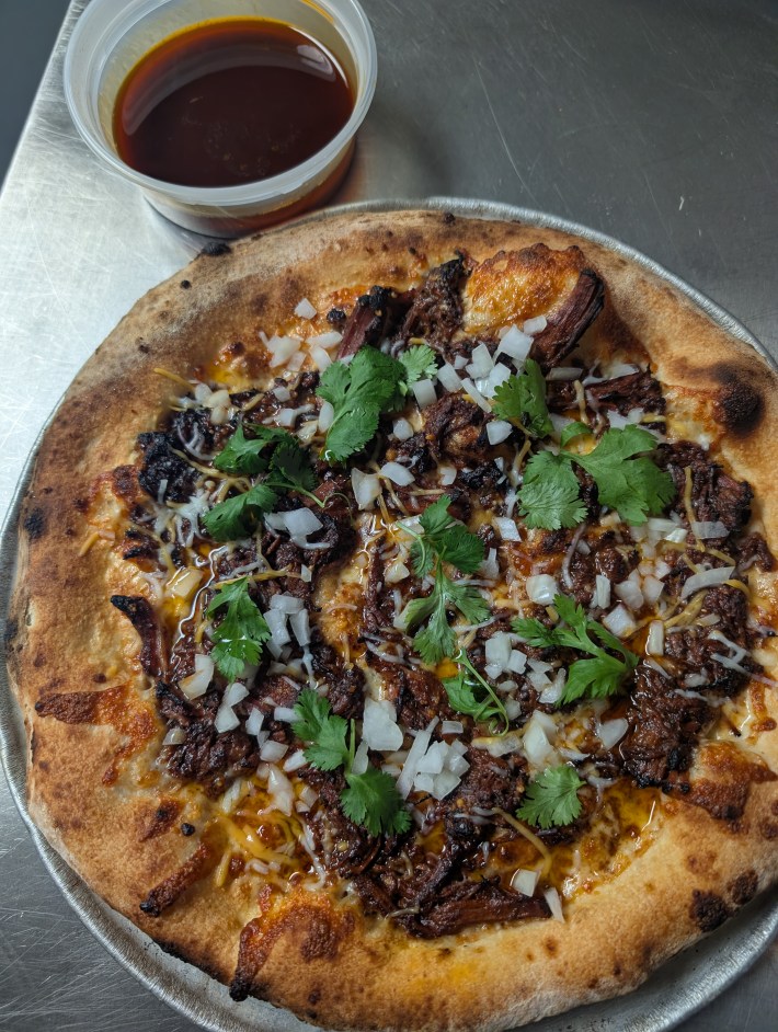 Gluten-free cauliflower-crust pizza topped with meat, onion and cilantro at Show Me Pizza in Austin.