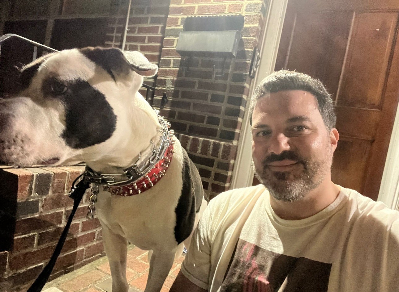 Franco Vendome sitting outside with his black-and-white rescue dog, Larry.