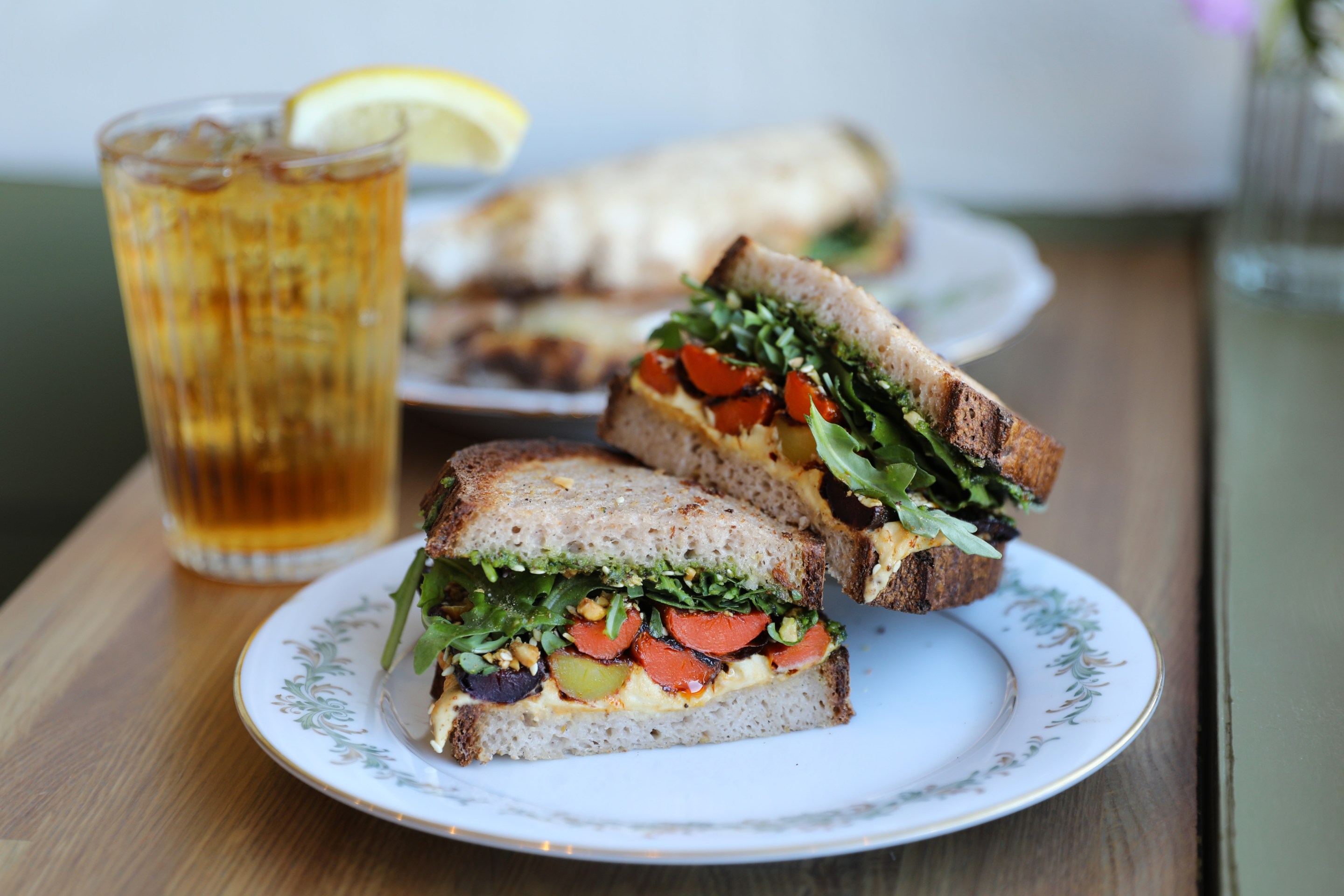 Gluten-free sandwich with roasted carrots, hummus, pesto and arugula.