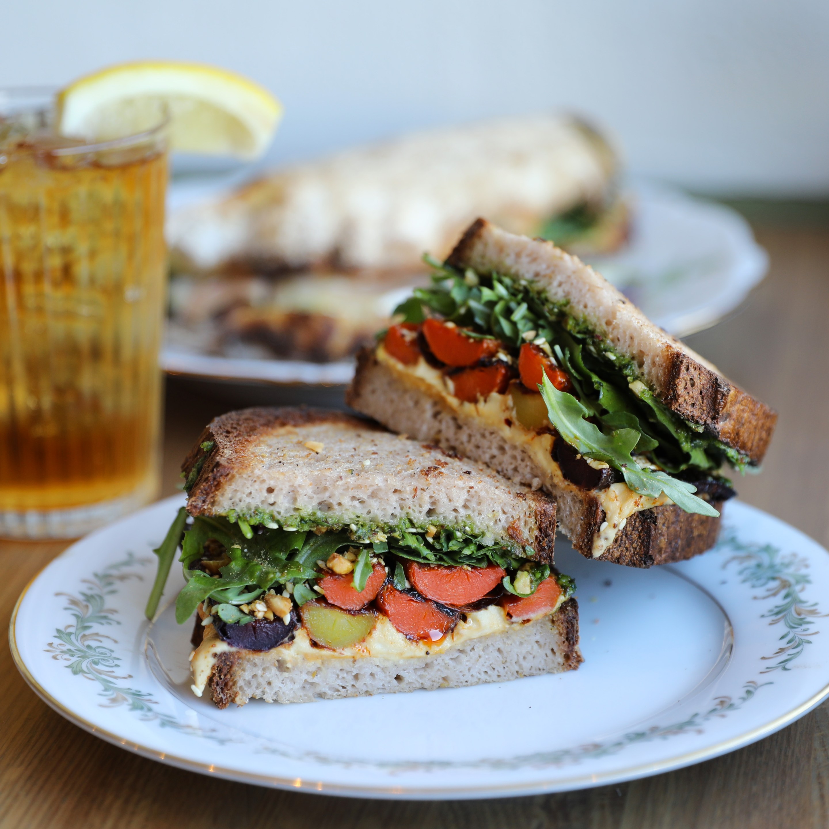 Gluten-free sandwich with roasted carrots, hummus, pesto and arugula.