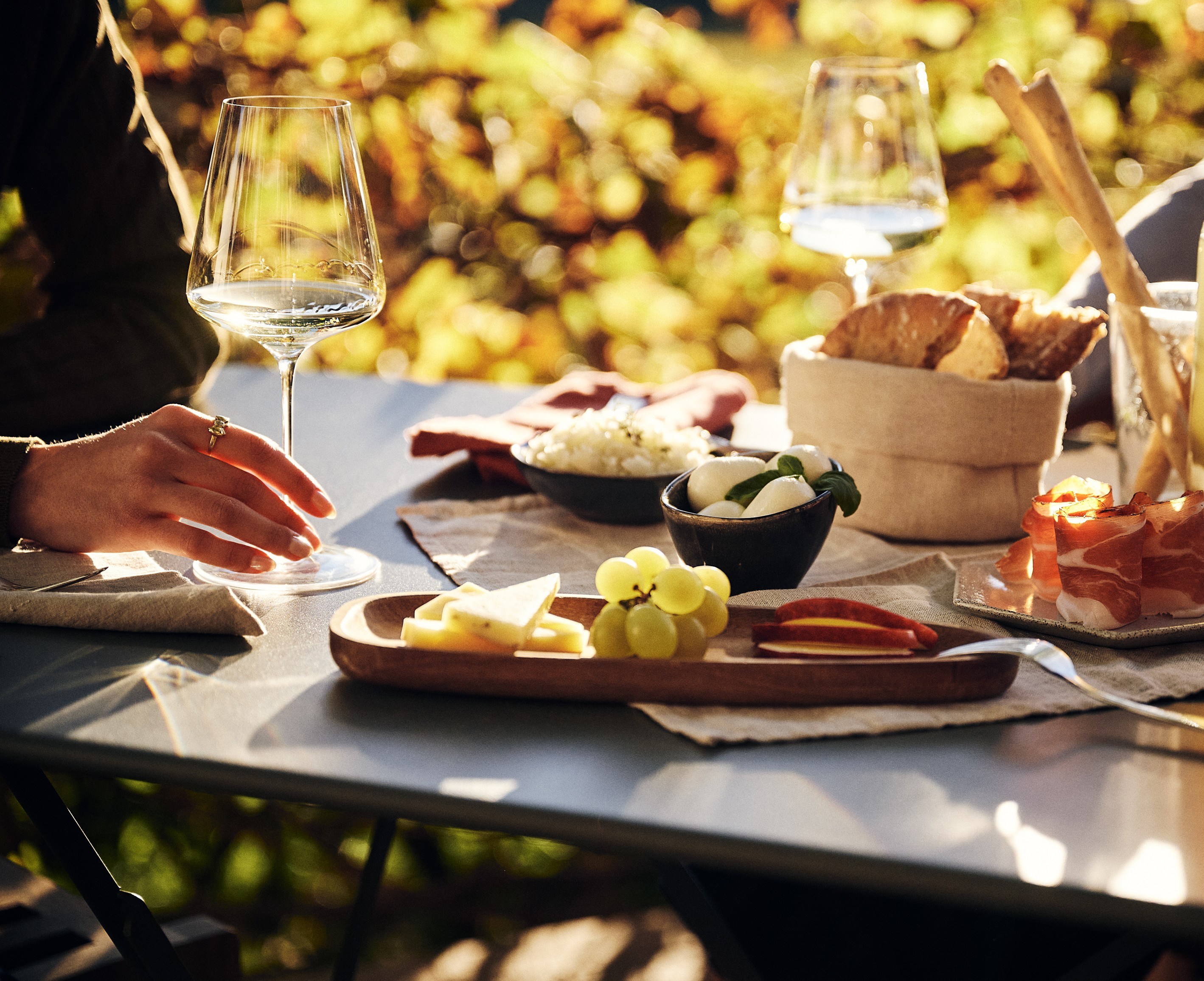 Wine, cheese, grapes, bread and cured meats served outdoors.