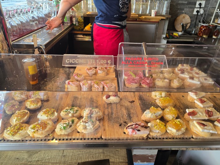 Assorted cicchetti displayed behind a bacaro counter in Venice.