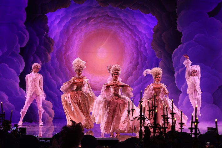 Performers in pale period-inspired costumes dance beneath purple lighting at Il Ballo del Doge.