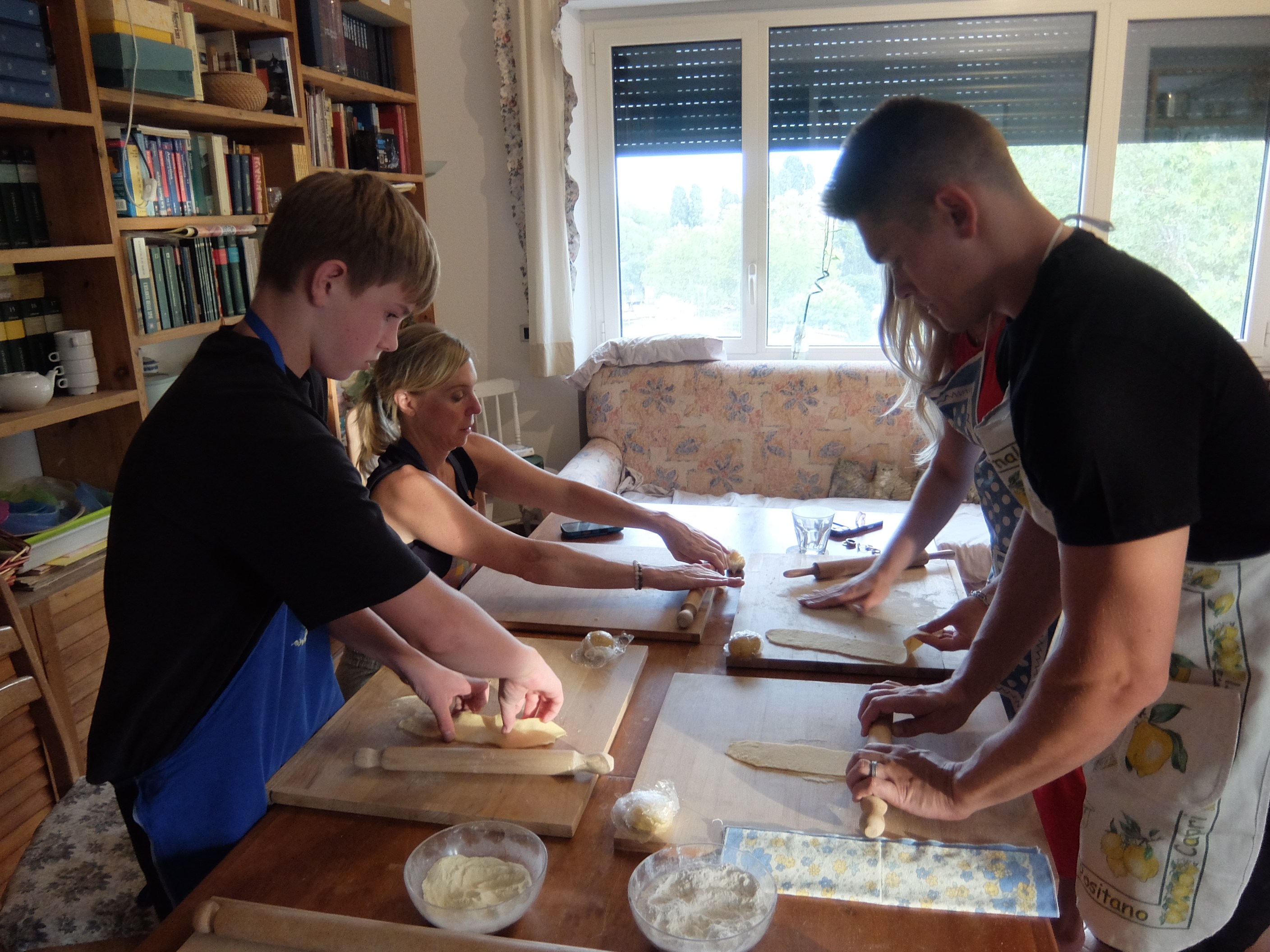 Cooking class participants roll pasta dough at a wooden table in Testaccio, Rome.