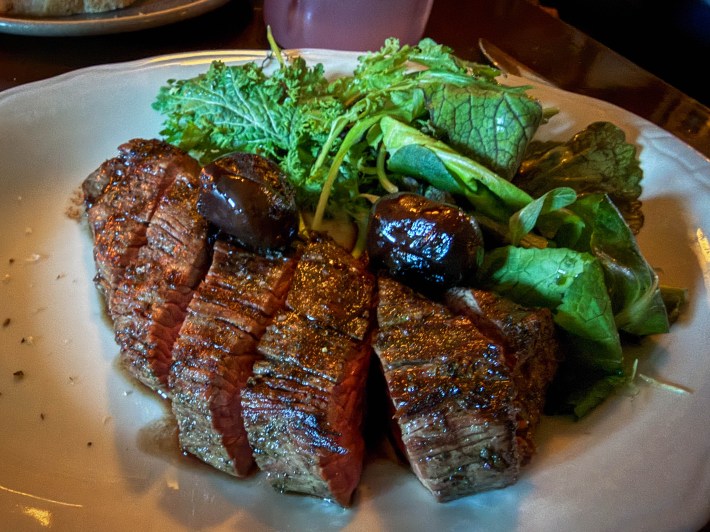 Sliced bison teres major served with leafy greens and cipollini onions at Glorietta.