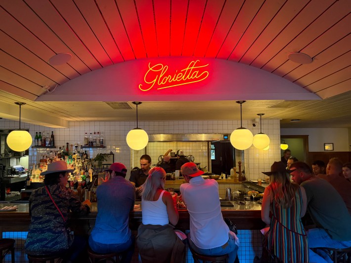 Guests seated beneath the glowing Glorietta sign at the restaurant’s bar.