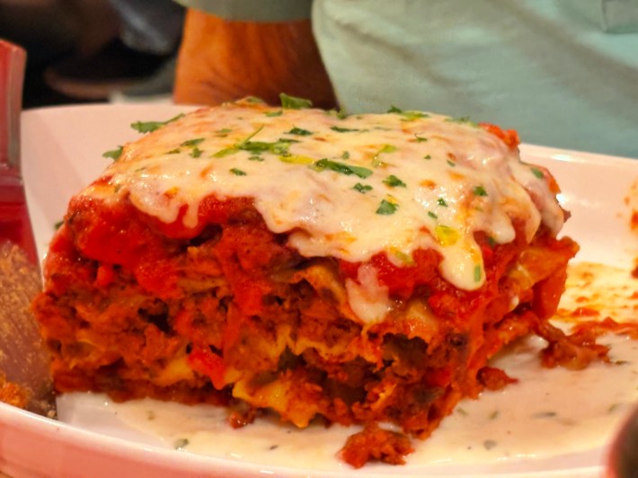 Slice of layered lasagna topped with melted cheese at Pino Bianco