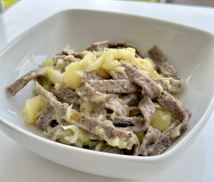 Bowl of pizzoccheri with potatoes, cabbage and melted cheese.
