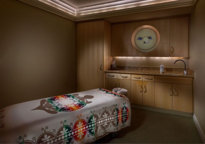 Massage table with a colorful patterned blanket inside a treatment room at Skʌ:nʌ́: Spa