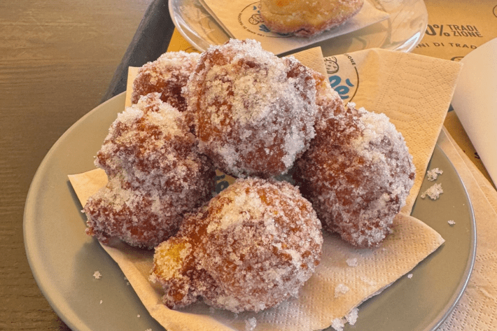 Sugar-coated balls of pizza fritta on a plate.