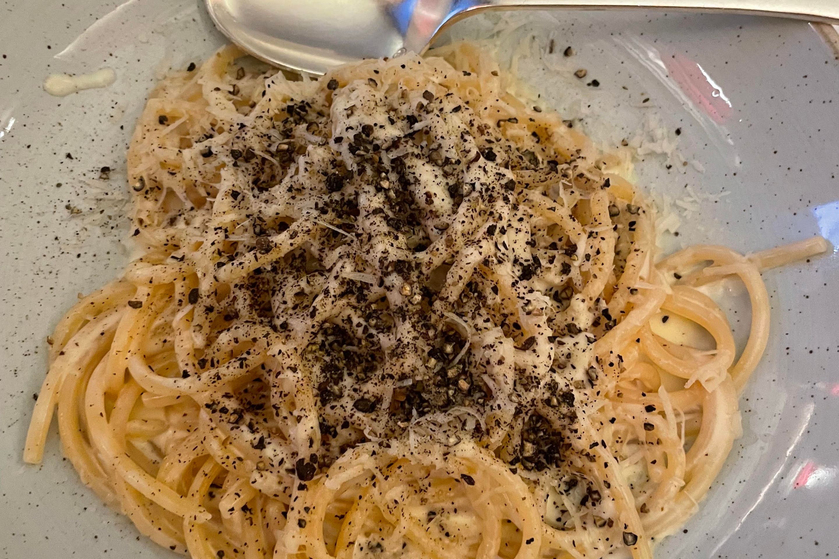 A bowl of cacio e pepe and a spoon.