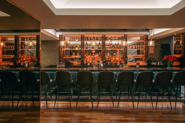 Audace’s bar with pendant lights, mirrored shelves and upholstered stools.