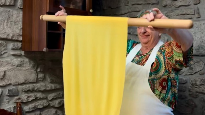 Alessandra Spisni lifts a sheet of handmade pasta to check its thinness.