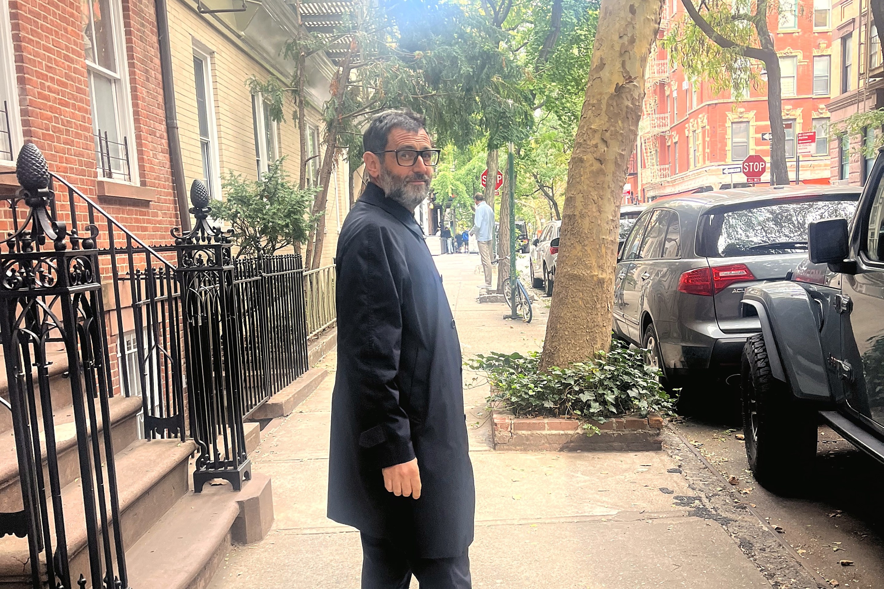 Iacopo Falai wearing glasses and a navy coat on a tree-lined sidewalk.