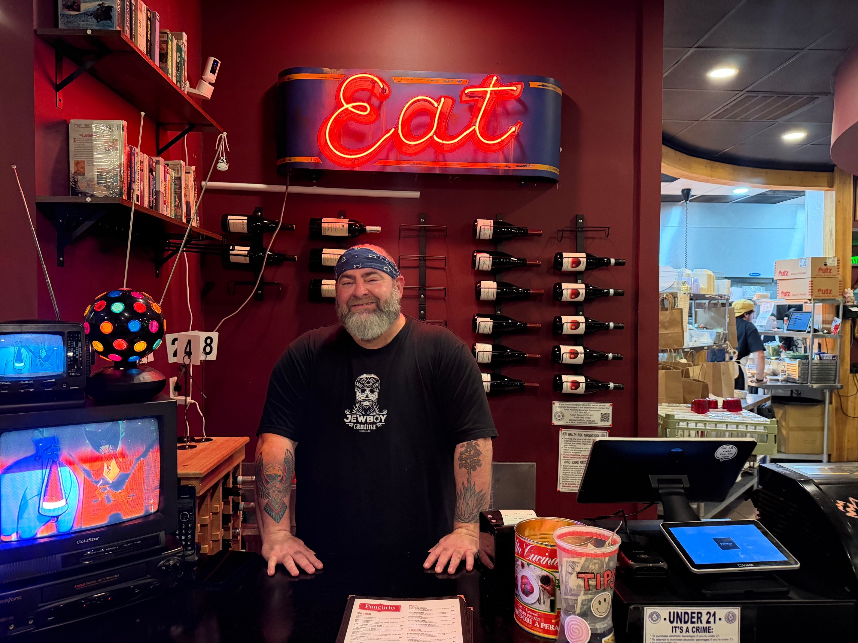 Mo Pittle behind Panciuto’s counter beneath a neon “Eat” sign.