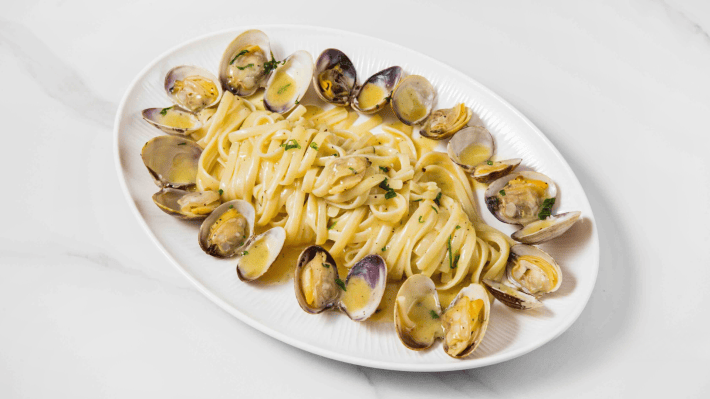 Linguine with clams in their shells on a white oval plate at Audace.