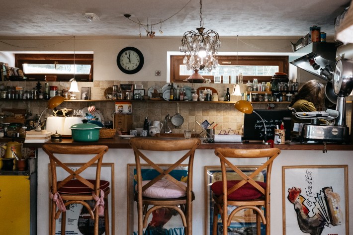 Kitchen at Maison Le Champ with wooden counter stools, cookware and a hanging chandelier.